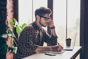 student studying with laptop and notepad, good posture, back mostly and neck mostly straight